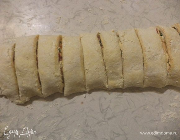 Тесто раскатать в тонкий прямоугольный пласт. Намазать пласт начинкой, аккуратно свернуть в рулет и нарезать кусочками толщиной 2 - 3 см, чтобы получились "улитки".