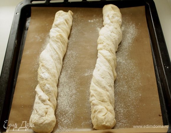 Выкладываем тесто на стол, делим пополам. Каждый кусок теста 2 раза прокручиваем через себя и выкладываем на противень с пекарской бумагой. Посыпаем мукой. 