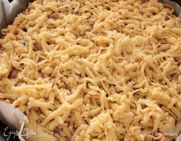 Достать тесто из морозильника и натереть его через крупную терку,равномерно распределяя по всей поверхности пирога.