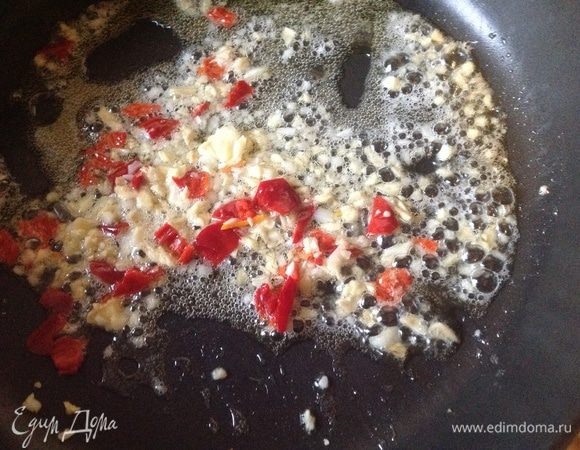 На сковороду или в вок влить немного масла и на сильном огне нагреть до легкого дымка. Положить неиспользованный чеснок, имбирь и чили, жарить около 30 секунд