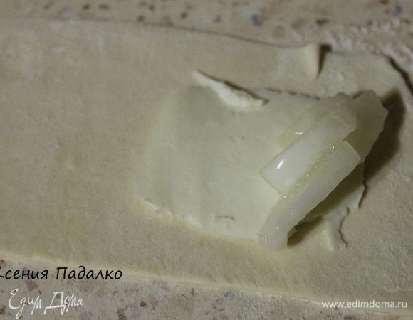 Тесто разморозить и раскатать слегка в длинные прямоугольники. На край теста кладем ломтик сыра.