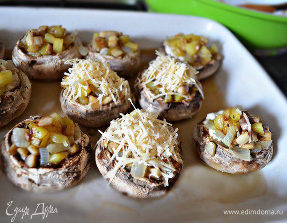 Наполнить шампиньоны приготовленной начинкой, посыпать сыром и запекать в нагретой до 180 г духовке ещё 10-15 мин.