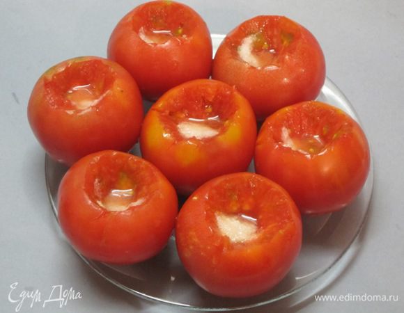 Чеснок очистить,  мелко нарезать. В каждый помидор насыпать пол чайной ложки соли и на кончике ножа сахара.