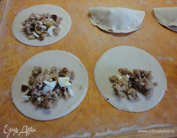 Слоеное тесто тонко раскатать и вырезать кружки диаметром около 12 см. В середину выложить начинку, свернуть пополам и хорошо защипать края.