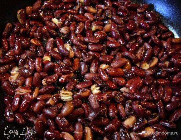 Большую сковороду разогреть. Обжарить на ней оставшуюся зиру пару минут. Когда раскроется аромат, добавить оливковое масло и выложить предварительно отваренную красную фасоль.
Обжаривать, помешивая, пока фасоль не станет хрустящей.
