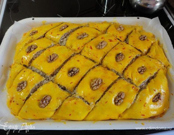 В ячично-шафрановую смесь добавить желток и смазать верх пахлавы.  Затем нарезать ромбами и на каждый выложить по четвертинке грецкого ореха. Выпекать в духовке 35 минут при температуре 180 градусов. 