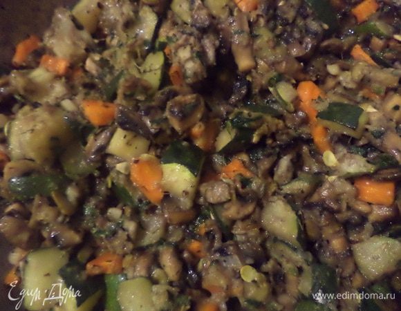 Лук обжарить на растительном масле до прозрачности.
До бавить шампиньоны, посолить, поперчить, обжарить грибы с луком.
Теперь добавить морковь и цуккини, тушить, пока не выпарится жидкость.
Добавить измельчённый чеснок, мелко рубленную зелень, половину тыквенных семечек, прованские травы, муку, перемешать.