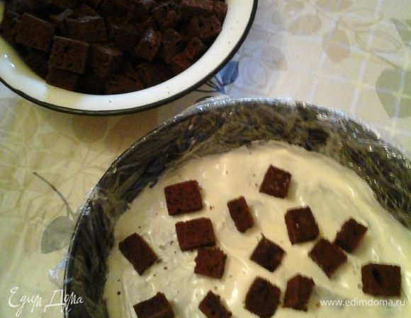 Берем форму и застилаем ее пищевой пленкой. Выливаем туда 3-4 ст ложки крема.. добавляем квадраты и фрукты с ягодами..2 слой также – крем, кубики, фрукты.. на фотке уже второй слой у меня..