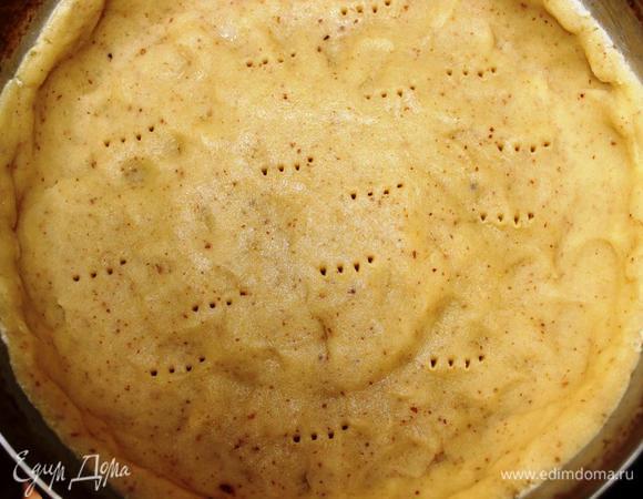 Разогреем духовку до 180 градусов. 
Разъемную форму диаметром 21 см смажем сливочным маслом, распределим по ней тесто, формируя бортики не менее 4 сантиметров в высоту, чтобы начинка поместилась. Наколем вилкой, накроем бумагой для выпечки, внутрь насыплем фасоль и отправим в духовку на 20 минут. 
