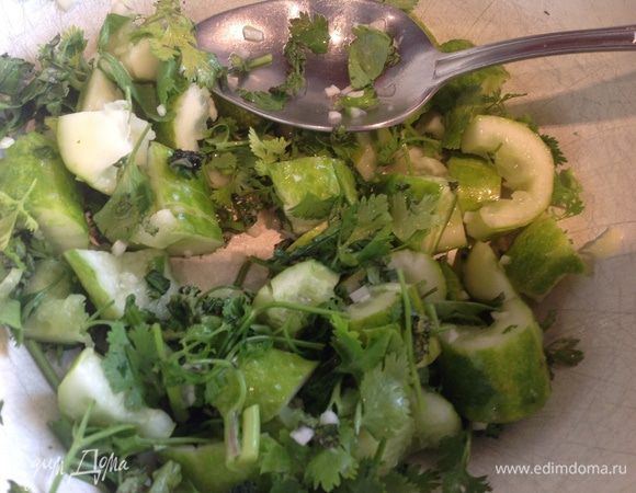 Смешайте огурцы, кинзу и чеснок в салатнике.