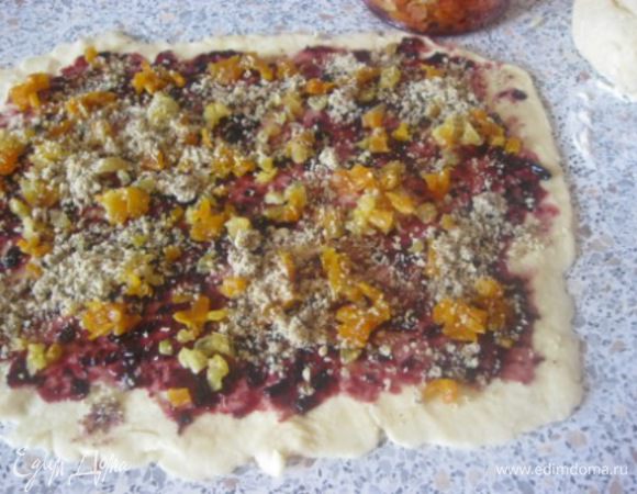 
Раскатать в тонкий пласт 1 кусок теста, размером 20 на 30 см.
Смазать вареньем, посыпать мелконарезанной курагой и изюмом, сверху посыпать рубленными грецкими орехами.
Так же поступить со вторым куском теста.