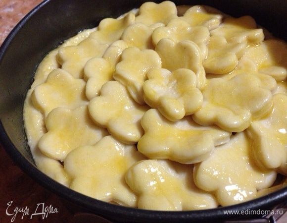 Меньшую часть теста раскатать,вырезать формой для печенья цветочки(или любую другую форму)и выложить их плотно поверх начинки.Смазать пирог взбитым яйцом.