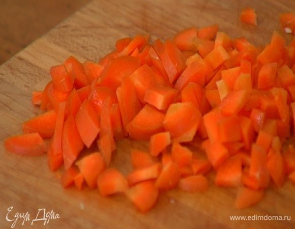 Морковь почистить, нарезать небольшими кусочками, выложить к луку с чесноком и обжаривать на медленном огне.