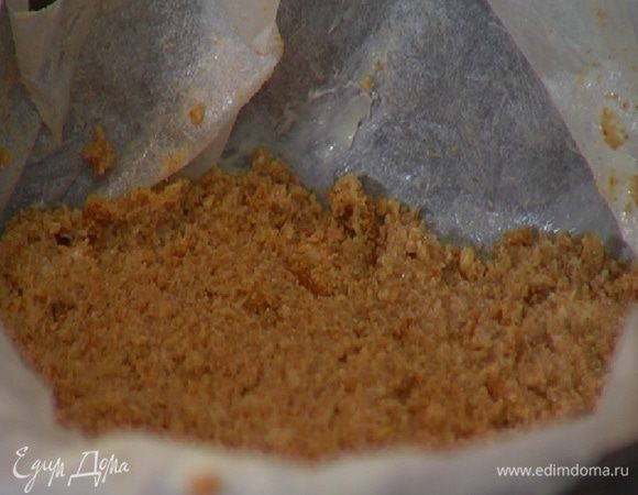 Небольшую разъемную форму для выпечки выстелить пищевой бумагой, смазанной оставшимся сливочным маслом, и выложить измельченное печенье так, чтобы получился тонкий корж.