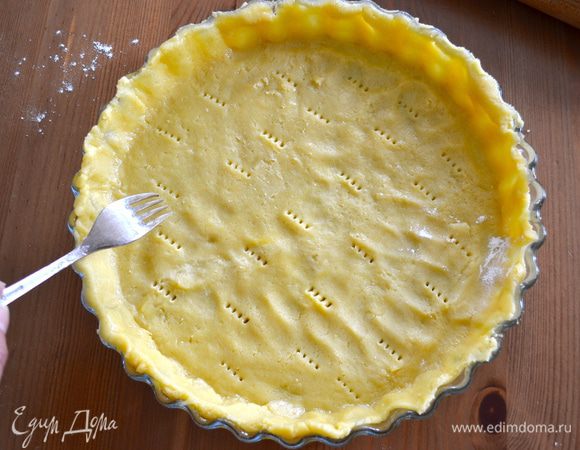 Перенести его в большую форму для выпечки (диаметр 28 см), сформировать небольшой бортик и наколоть тесто вилкой.