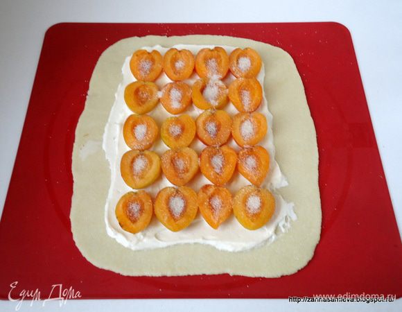 Не доходя до краев теста нанести смесь из крем - чиза и плавленого сыра, сверху выложить половинки абрикоса, присыпать его сахаром.