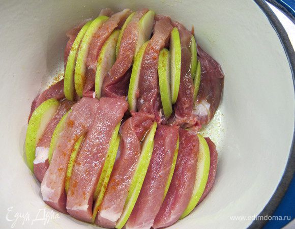 Мясо помыть, обсушить. Сделать глубокие надрезы. Посолить, поперчить, сбрызнуть вином и оливковым маслом и оставить мариноваться на пару часов.
Яблоко помыть, разрезать пополам, удалить сердцевину и нарезать толстыми ломтиками.
Ломтики вставить в разрезы, уложить мясо в жаропрочную посуду и накрыть крышкой или фольгой. 