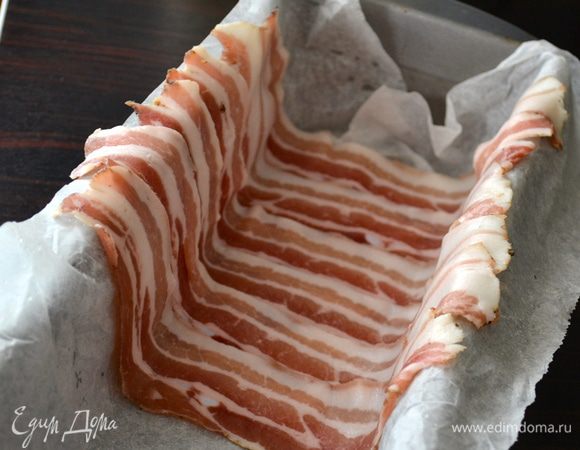 Форму для кексов выложить пекарской бумагой, предварительно смоченной водой и как следует отжатой. Выложить всю форму полосками бекона (грудинки).