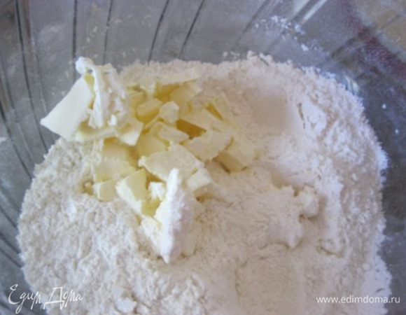 К миске с мучной смесью добавить нарезанное сливочное масло.