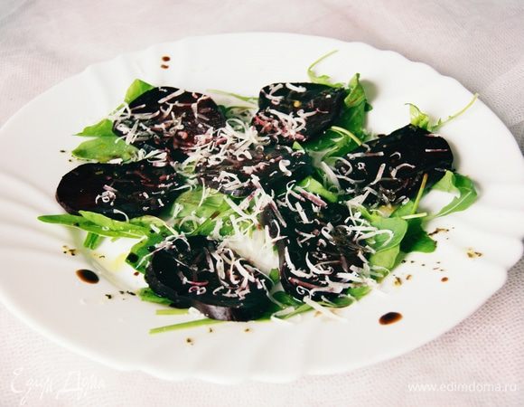 Вареную свеклу режем на кружочки. Руколу режем или рвем и выкладываем на тарелку.
Сверху укладываем кружочки свеклы.
Сбрызгиваем маслом и посыпаем тертым пармезаном.