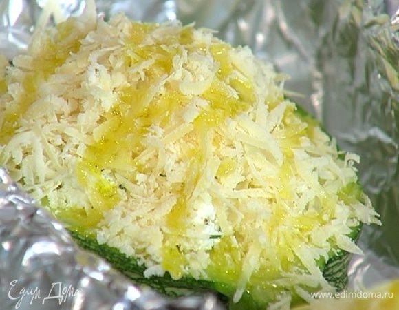 Узкую форму для запекания выстелить фольгой, поместить цукини с творогом, посыпать натертым сыром и сбрызнуть оливковым маслом.