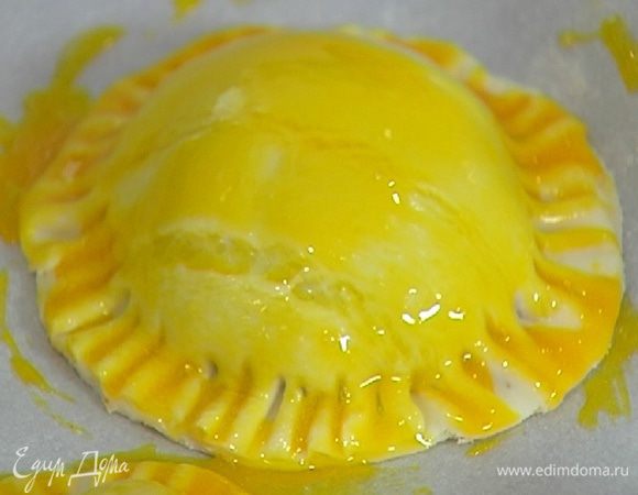 Желток слегка взбить с солью и смазать пирожки.