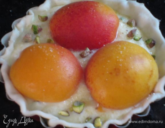 На тарталетки выложить крем,сверху выложить половинки абрикосов,посыпать тростниковым сахаром и рублеными фисташками.Выпекать в разогретой до 180 ° С духовке 35-40 минут.