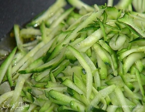 Цукини натереть на крупной терке, отправить в сковороду с чесноком, перемешать и обжаривать 1–2 минуты.