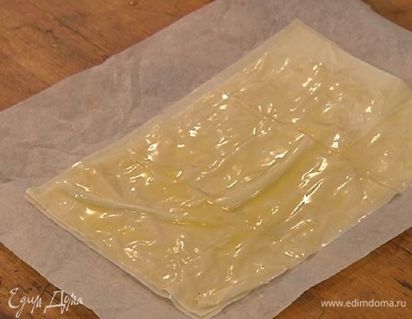 Листы теста фило разрезать пополам, три листа смазать сливочным маслом и уложить друг на друга на противень, выстеленный бумагой для выпечки.