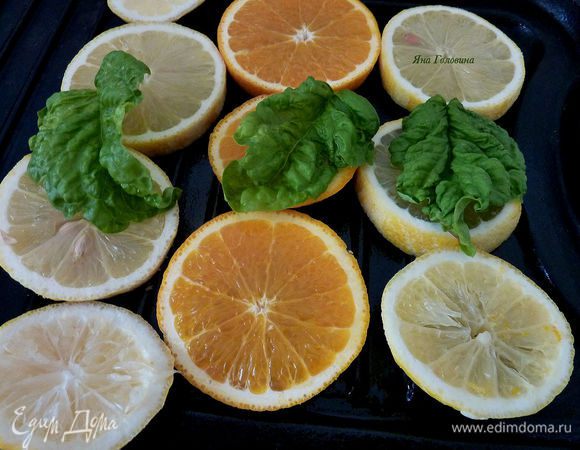 Аккуратно промазать сковороду маслом растительным. Рыбу посолить и поперчить. Цитрусовые порезать и разложить на сковороду.

Сверху разложить зелень по вкусу.
