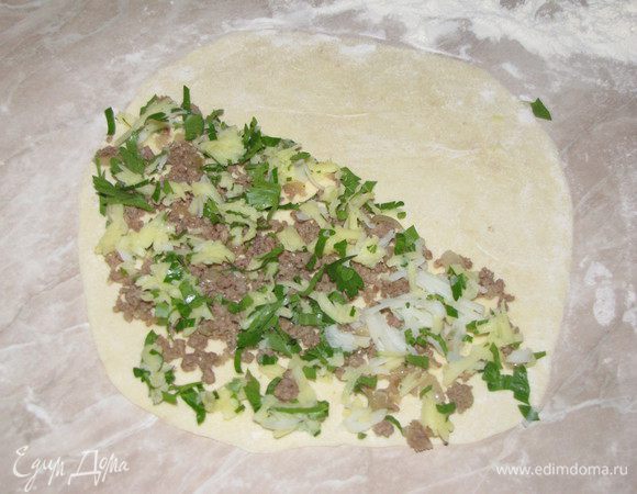 Присыпать рабочую поверхность мукой и раскатать шарик теста в очень тонкую лепешку. В Турции эту лепешку наматывали на скалку.))) На половину лепешки выложить тонким слоем начинку.