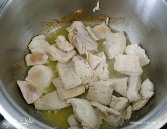 Растопить сливочное масло в большой огнеупорной кастрюле и обжарить в ней нарезанные полосками куриные грудки на умеренном огне в течение 5 минут.