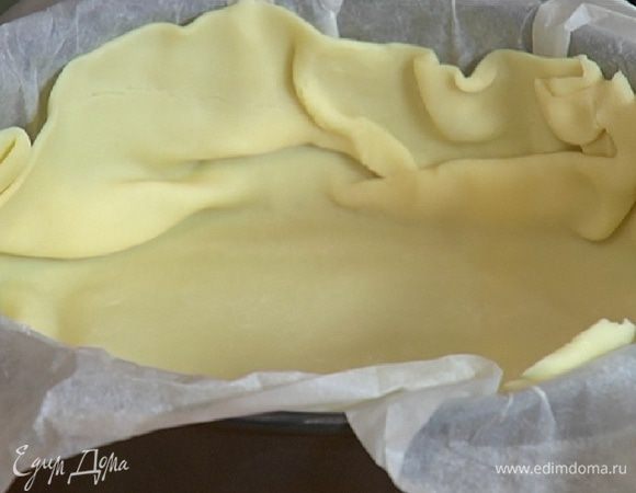 Разъемную форму выстелить бумагой для выпечки и выложить песочный корж так, чтобы получились бортики.