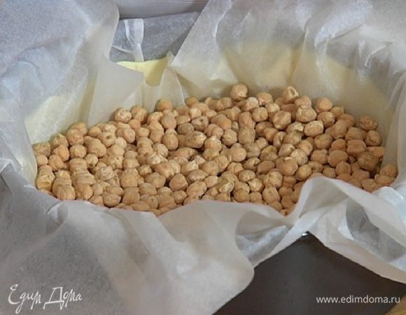 На тесто поместить еще один лист бумаги для выпечки, всыпать горох и выпекать корж в разогретой духовке 15 минут.