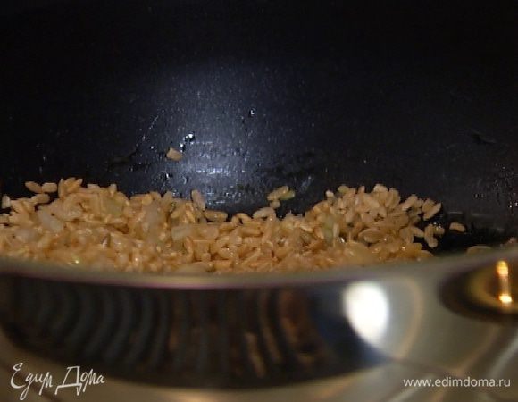 Всыпать рис и, помешивая, обжаривать около минуты, пока он не станет прозрачным.