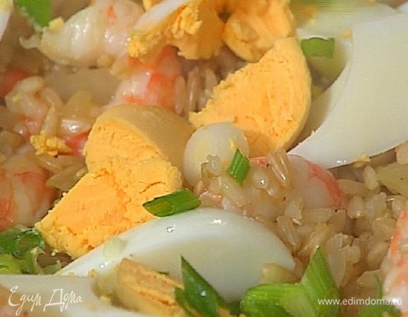 Выложить рис с креветками на блюдо, украсить нарезанными яйцами и луком.