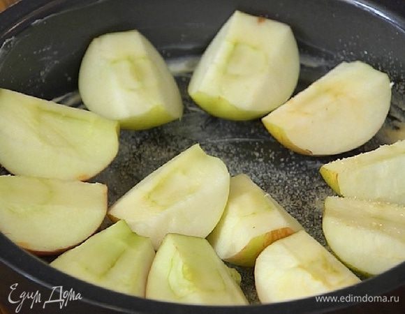 Форму для выпечки смазать оставшимся сливочным маслом, присыпать оставшимся сахаром, разложить яблоки срезами вверх, а сверху выложить тесто.