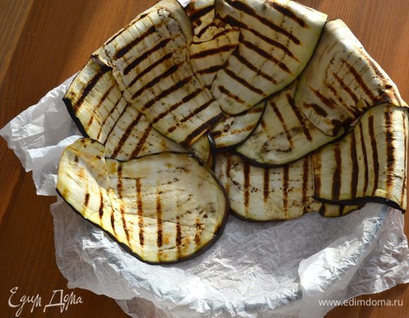 Духовку включить на 180 С. Теперь подготовить форму для запекания (диаметром 22 см). Выложить форму пекарской бумагой, предварительно смоченной в воде и отжатой. Теперь выложить по кругу баклажаны. Так как мои баклажаны были не очень длинными, я выкладывала в два "яруса". Первый слой по кругу к центру и второй с концами, свисающими с краев формы...