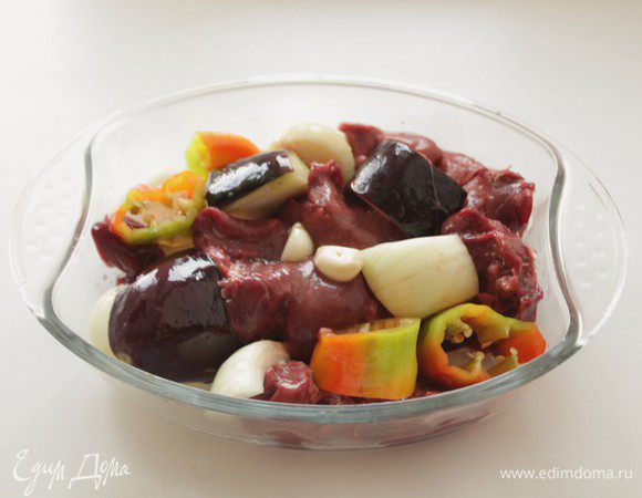 Нарезать баклажаны, перец, лук крупными кусочками и поместить в огнеупорную форму.
Чесночные зубки поместить целиком. Туда же поместить печень.  Посолить. Полить растительным маслом продукты и поставить в разогретую духовку. 