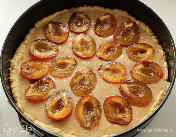 Наполнить корж кремом, разложить сверху половинки слив. Выпекать пирог около 30 минут при температуре 180°C.