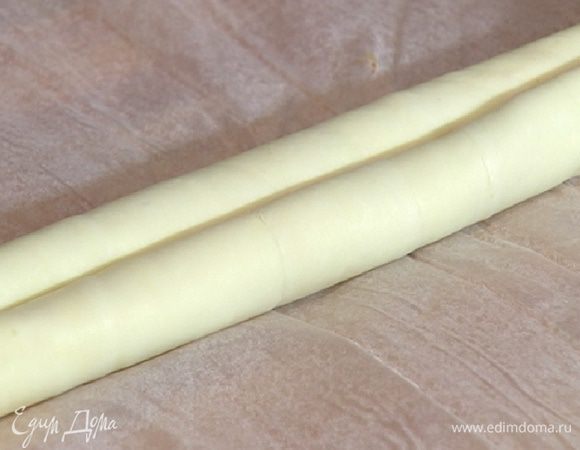 Пласт теста смазать взбитыми желтками (немного оставить), посыпать сахаром, корицей и свернуть до середины в рулет, а затем так же закрутить другой край теста навстречу первому.