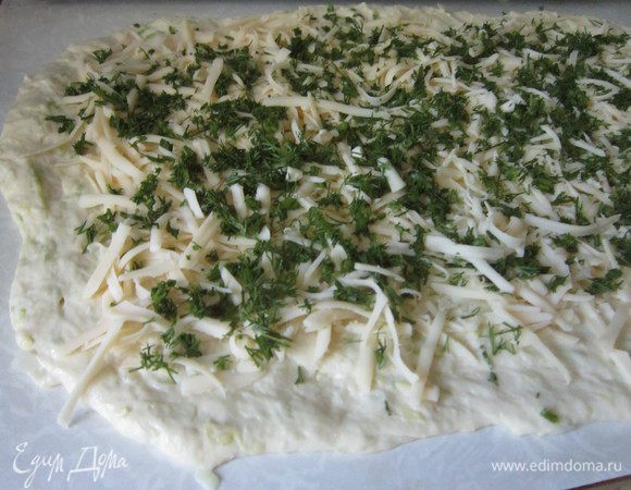 Смазать оливковым маслом стол и руки, сформировать из теста прямоугольник, посыпать его сыром и зеленью.