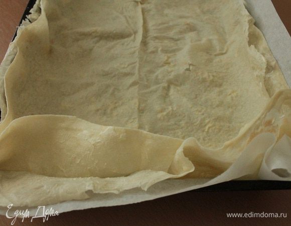 Форму для запекания выстелить пергаментом(у меня антипригарный).Выкладываем лист лаваша,обильно смазываем его сметаной,выкладываем еще один лист лаваша,слегка придавливаем руками.Лаваш надо выбирать самый тонкий.Мне попалась упаковка с бракованными листами,края толстые,а серединка слегка порванная,так что выбирайте качественный.Для смазывания лаваша понадобится дополнительное количество сметаны,примерно 80-100 гр,для этого можно использовать сметану с самой низкой жирностью,она нужна для того,что бы лаваш не был сухим после выпечки и у пирога была красивая румяная корочка.