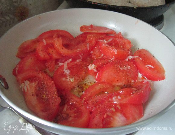Помидоры ошпарить кипятком, окунуть в холодную воду и очистить от шкурки, нарезать дольками. В сковороде разогреть масло, зубчик чеснока очистить, натереть на мелкой терке, обжарить. Добавить дольки томатов, перемешать, накрыть крышкой, огонь отключить, дать помидорам пропитаться чесночным маслом.