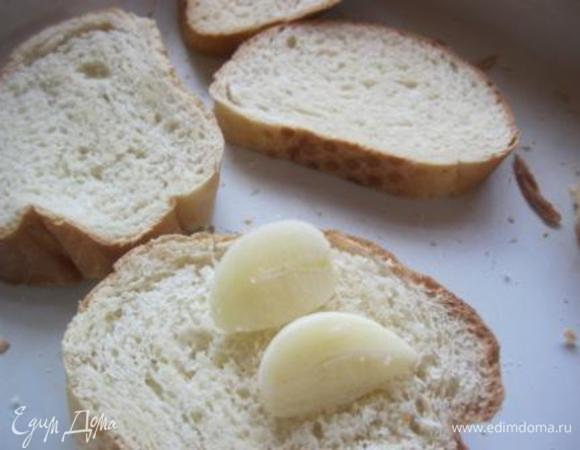 Батон подсушить в духовке.
Чеснок разделить пополам и натереть им гренки.