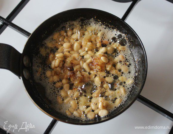 Сливочное масло растопить в сковороде, добавить размягчившийся чеснок и размять его. Добавить кедровые орешки и продолжать готовить все вместе, помешивая.