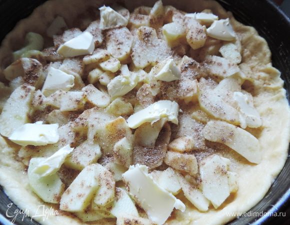 Тесто делим на 3/4 и 1/4. Большую часть теста распределяем руками
по форме 26 см (это удобно делать руками, слегка присыпая тесто мукой), предварительно выстилаем дно формы бумагой для выпечки. Выкладываем сверху яблоки, посыпаем сахаром, корицей, ванильным сахаром. Выкладываем в хаотичном порядке небольшие кусочки сливочного масла.