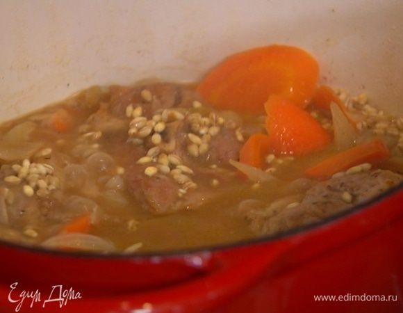 Добавить вымытую и просушенную перловку, посолить, перемешать держать на огне еще 30‒50 минут, пока мясо и перловка не будут готовы.