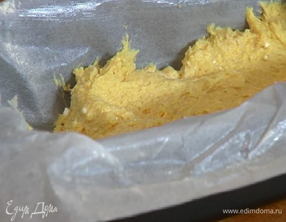 Бумагу для выпечки смазать сливочным маслом, выстелить небольшую продолговатую форму и равномерно распределить тесто.