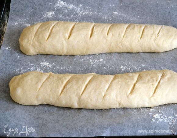 Выложить на противень, застеленный пекарской бумагой. Острым лезвием сделать надрезы наискосок.